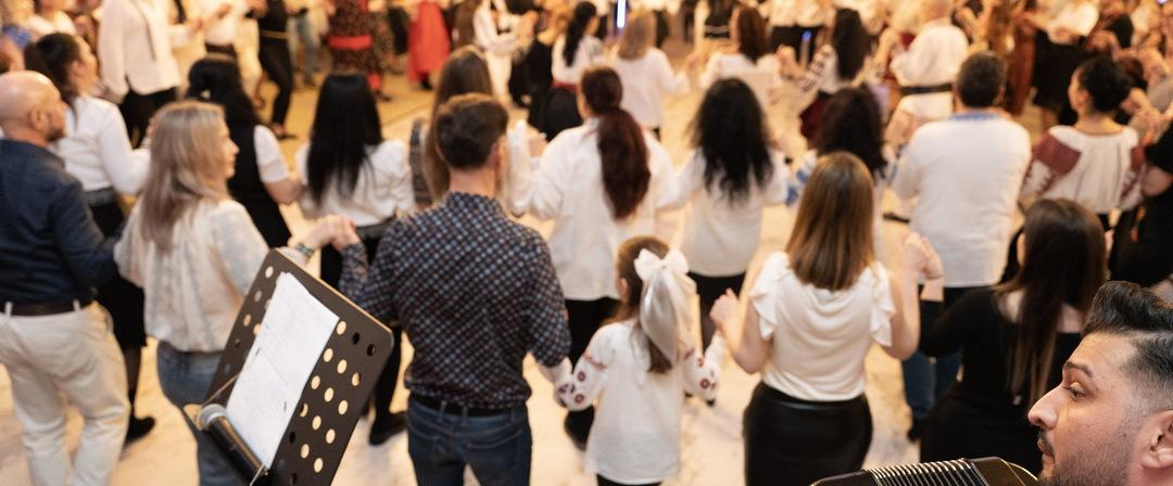 Copii și adulți dansând împreună într-o horă